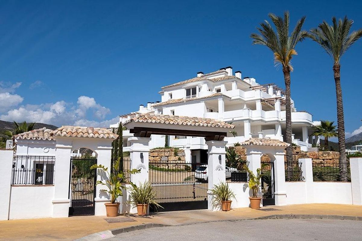 Toegangspoort tot een stijlvol penthousecomplex met palmbomen in Marbella, Costa del Sol, Spanje.