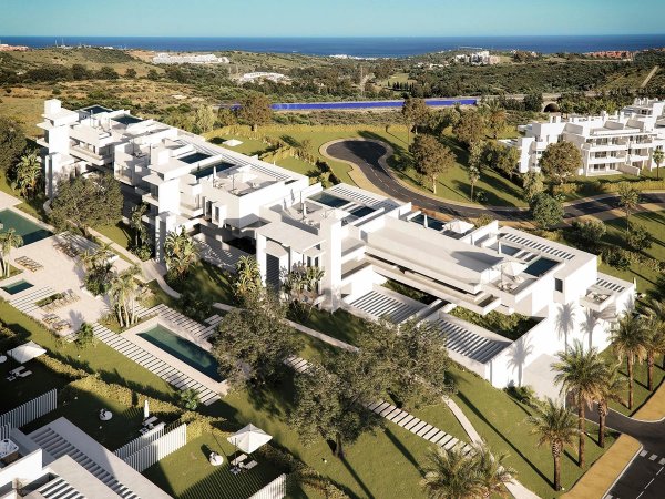 Luchtfoto van een modern appartementencomplex in Casares, Costa del Sol met weelderige tuinen en zwembaden.