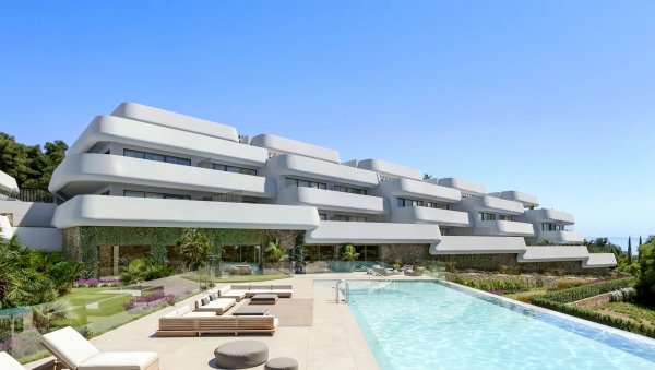 Modern appartementcomplex aan de buitenzijde met zwembad en tuinen in Casares, Costa del Sol onder een blauwe lucht.