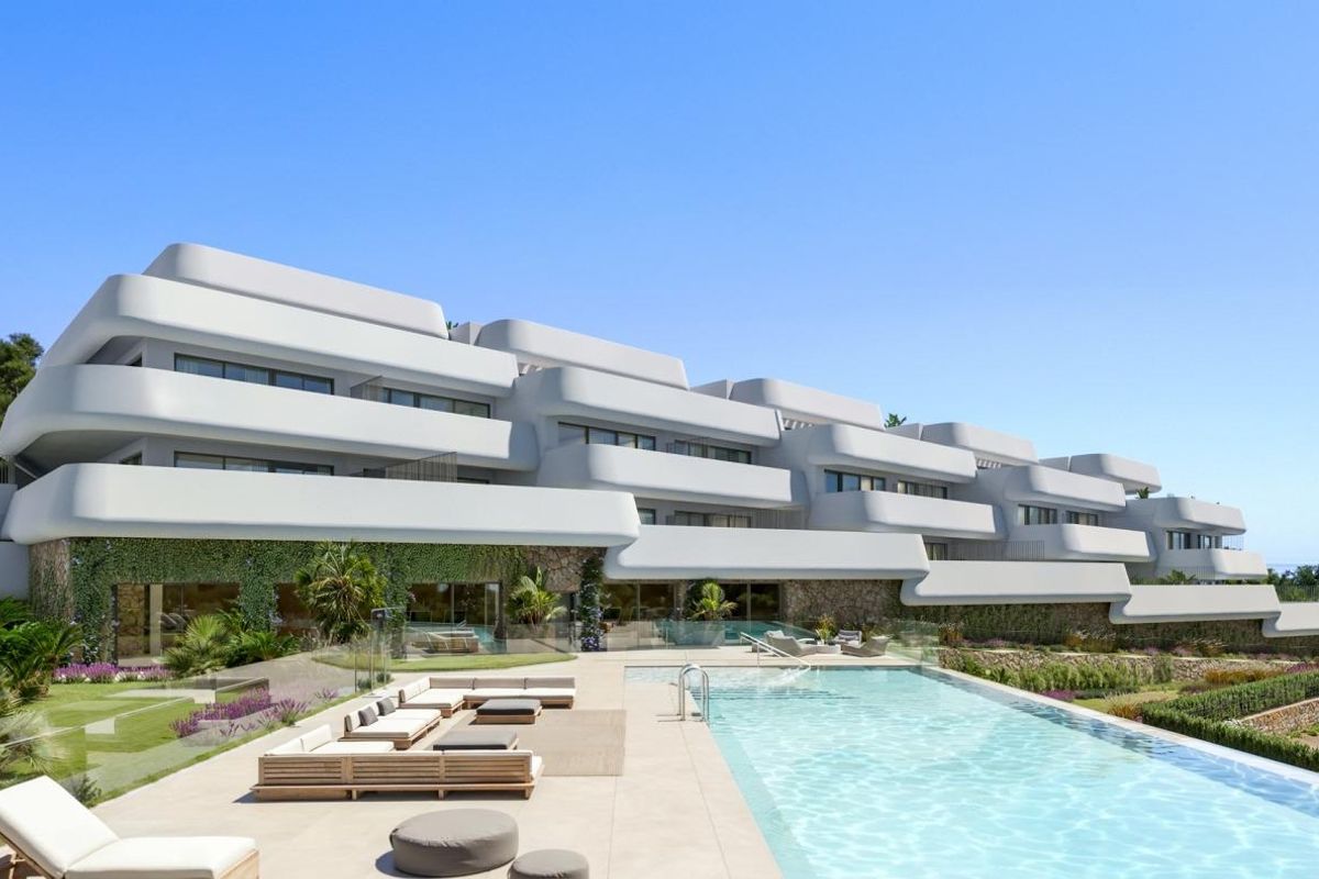 Modern appartementcomplex aan de buitenzijde met zwembad en tuinen in Casares, Costa del Sol onder een blauwe lucht.