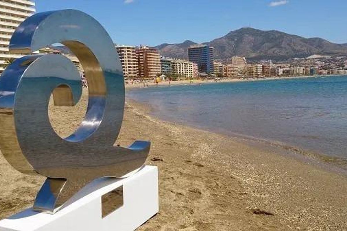 Beeldhouwwerk bij het strand in Fuengirola, met de skyline van de stad op de achtergrond, een mix van kunst en natuur.