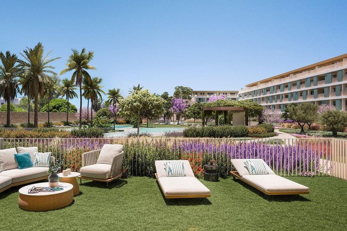 Lush garden area with loungers and purple flowers beside an apartment complex in Denia, Costa Blanca North.