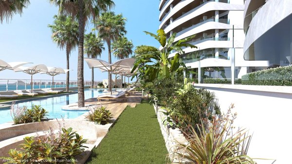 Luxurious property garden area with palm trees and sun loungers in La Manga del Mar Menor, Spain.