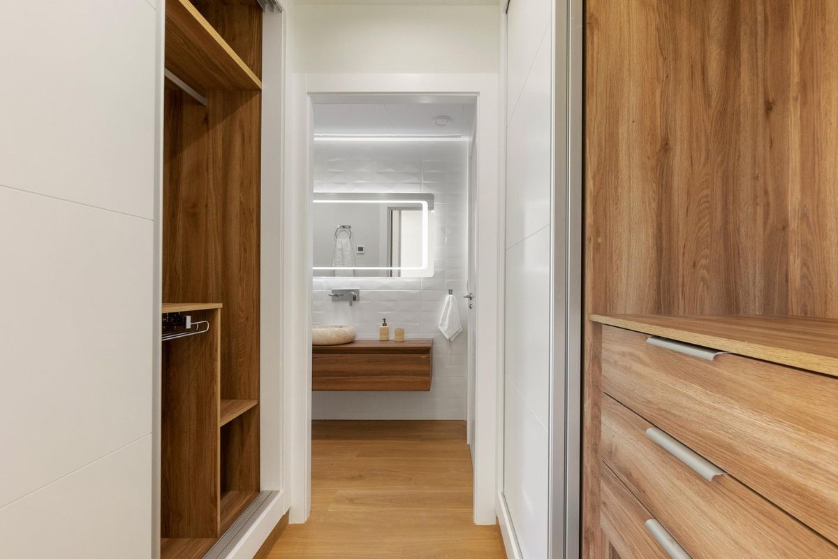 Inloopkast die naar een stijlvolle badkamer in een Rojales villa leidt, met houten elementen.