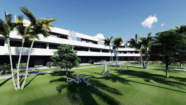 Buitenzicht op een modern appartementencomplex in Guardamar del Segura met palmbomen en een groene gazon.