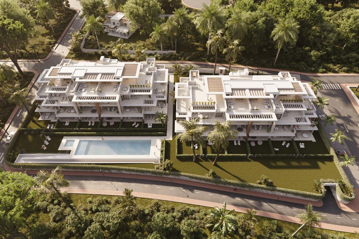 Luchtfoto van twee luxe gebouwen met een gedeeld zwembad in Estepona, omringd door groen en palmbomen.
