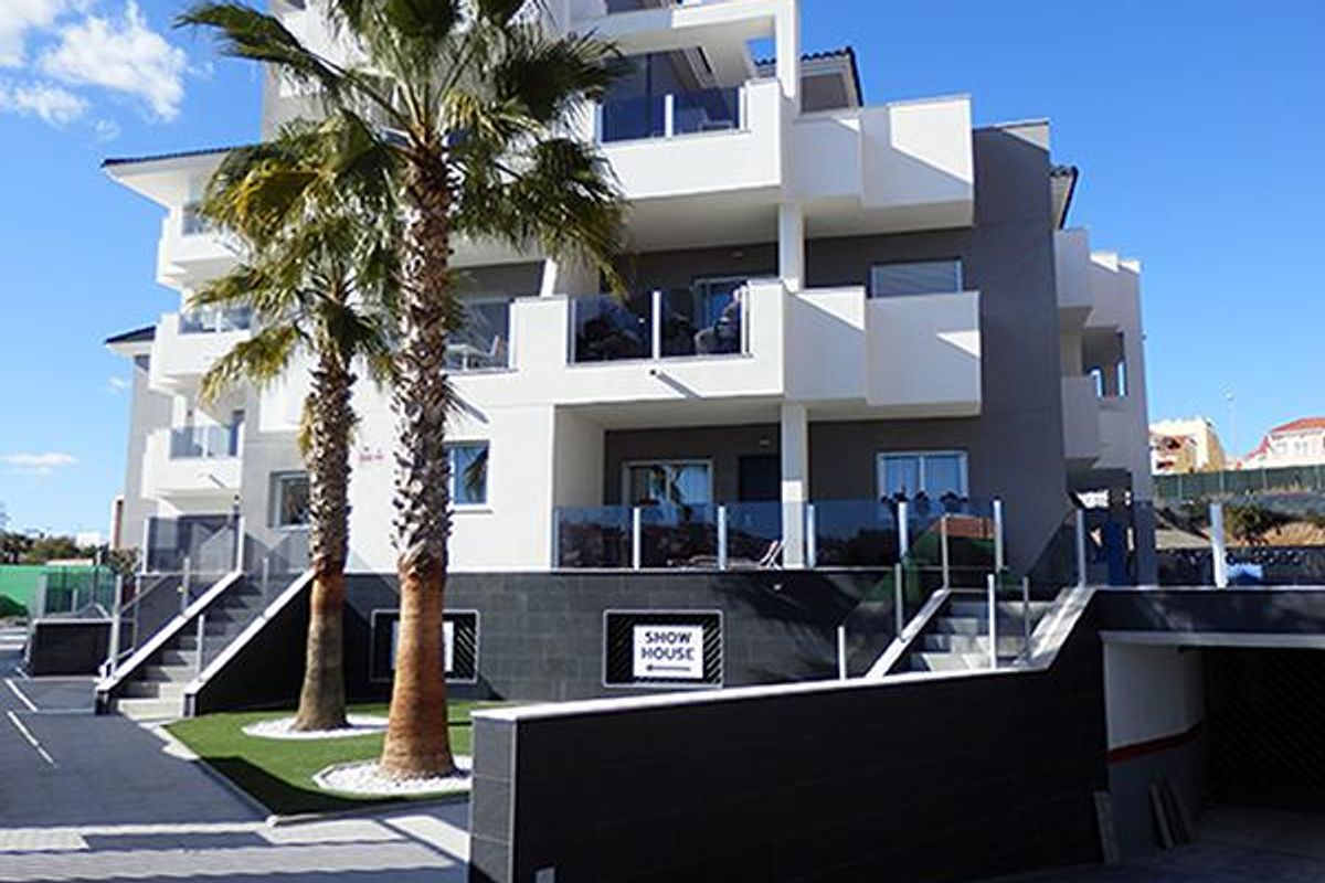 Voorkant van het moderne appartementencomplex met palmbomen, gelegen in Orihuela Costa, Spanje.