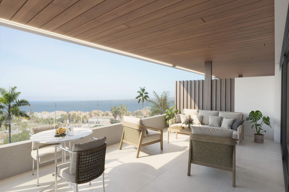 Overdekt terras met comfortabele zitplaatsen en uitzicht op de oceaan in een appartement op de begane grond in Manilva, Costa del Sol.