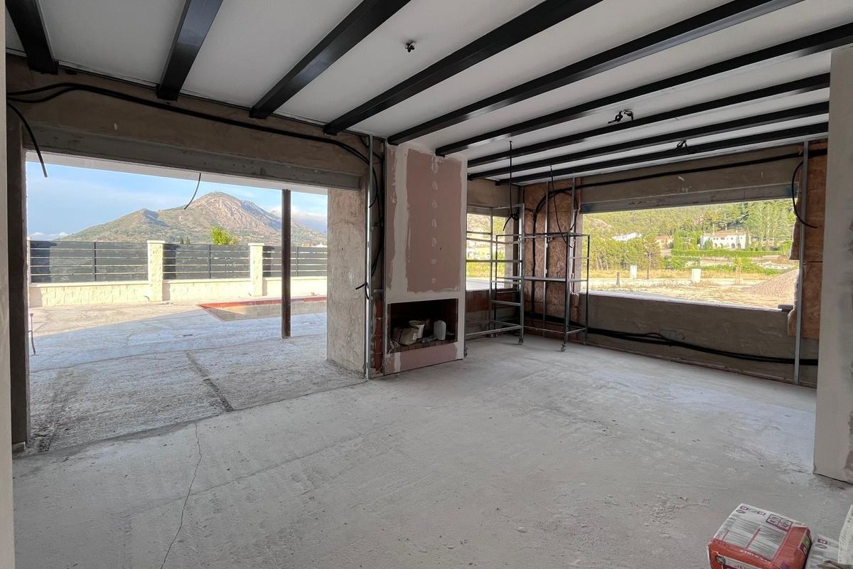 Interieur van de woonkamer in de villa, met grote ramen en uitzicht op de bergen in Penaguila.