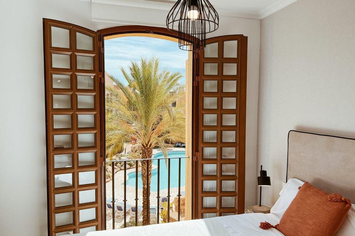 Heldere slaapkamer met balkondeuren die uitkomen op het uitzicht op het zwembad in het appartement in Cuevas Del Almanzora.