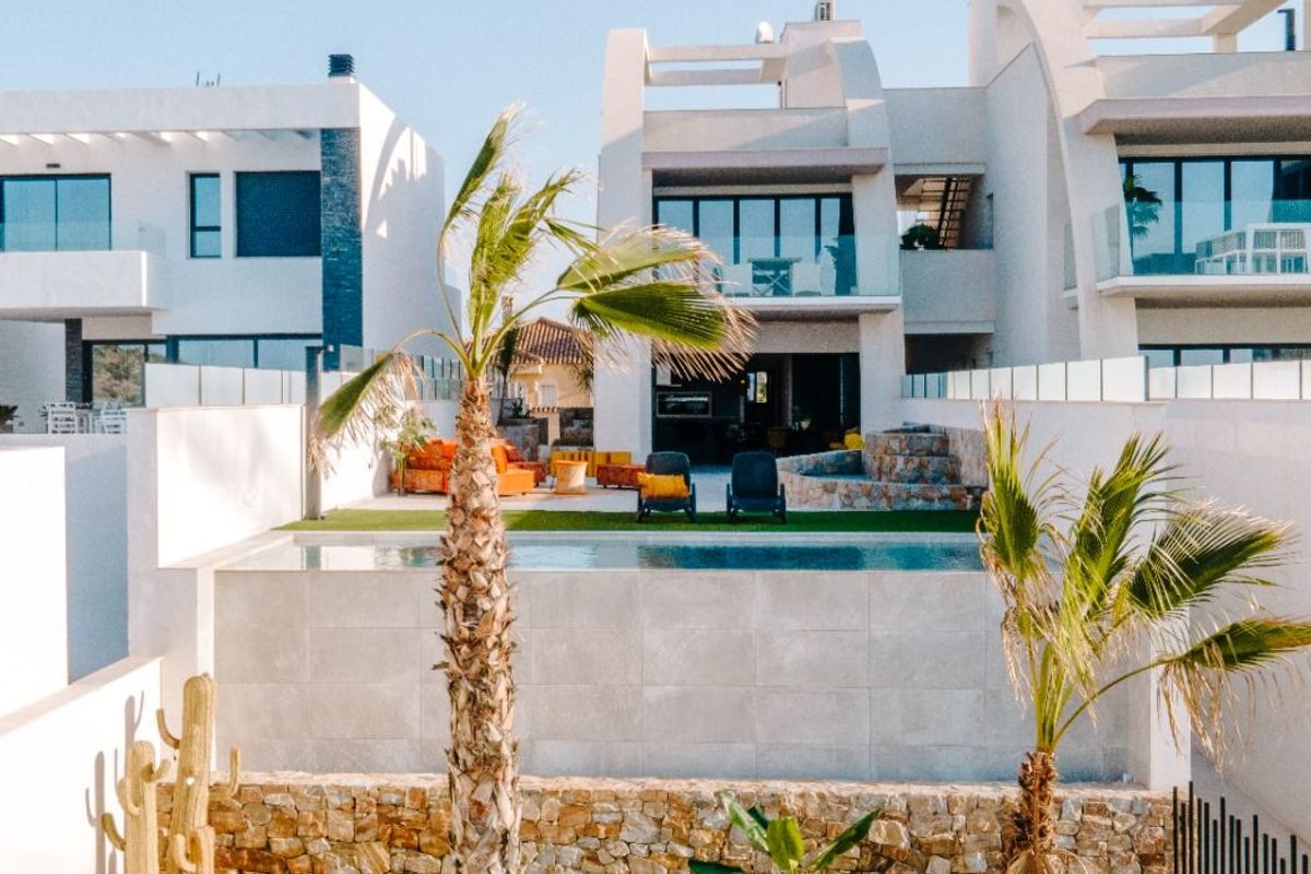 Goed onderhouden tuin met palmbomen en zitplaatsen, rondom een appartement op de begane grond in Rojales, Costa Blanca.