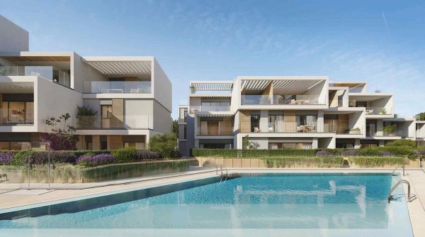 Buitenzicht van een modern appartementencomplex met zwembad in Marbella, Costa del Sol, met weelderig groen.