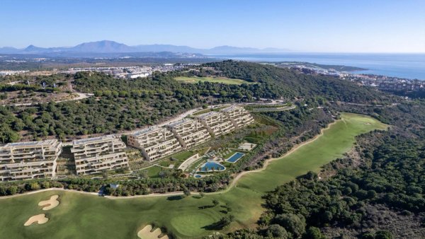 Luchtfoto van een modern appartementencomplex in San Roque, Costa del Sol, omringd door weelderige groene heuvels.