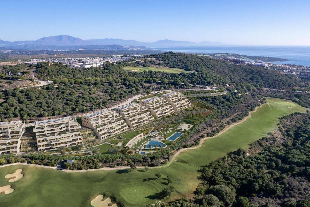 Luchtfoto van een modern appartementencomplex in San Roque, Costa del Sol, omringd door weelderige groene heuvels.