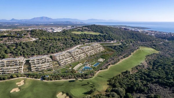 Luchtfoto van een modern appartementencomplex in San Roque, Costa del Sol, omringd door weelderige groene heuvels.
