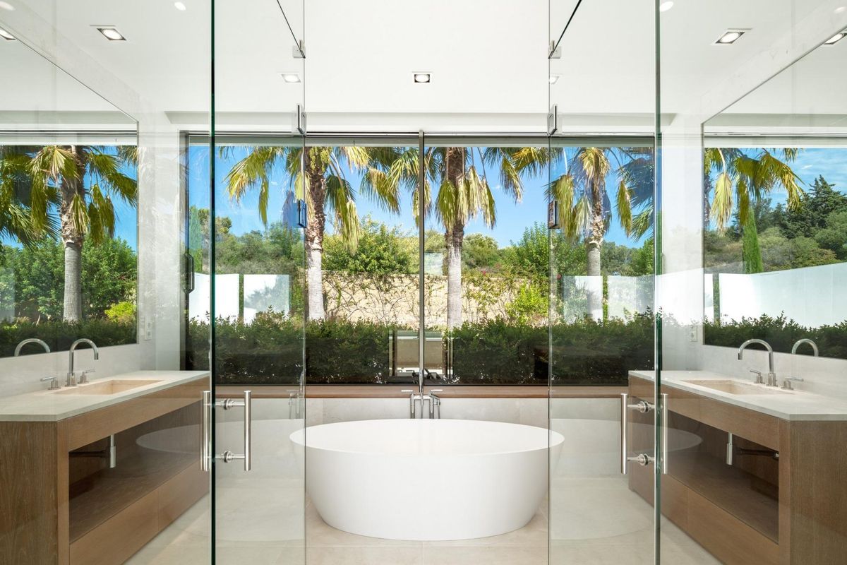 Luxe badkamer met vrijstaand bad, met uitzicht op tuinen en palmbomen in een villa in Casares.