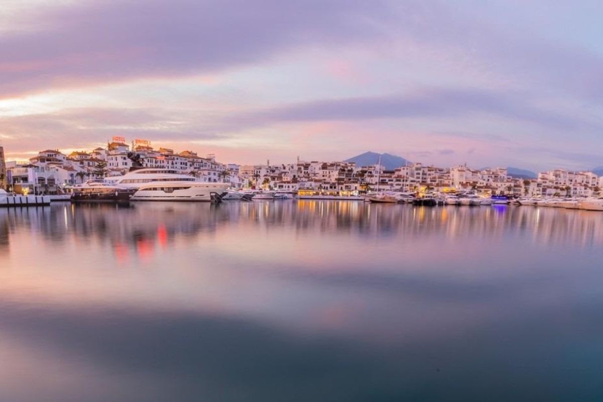 Adembenemend zonsondergang panorama van de jachthaven in Marbella, Costa del Sol, met jachten die in het water reflecteren.