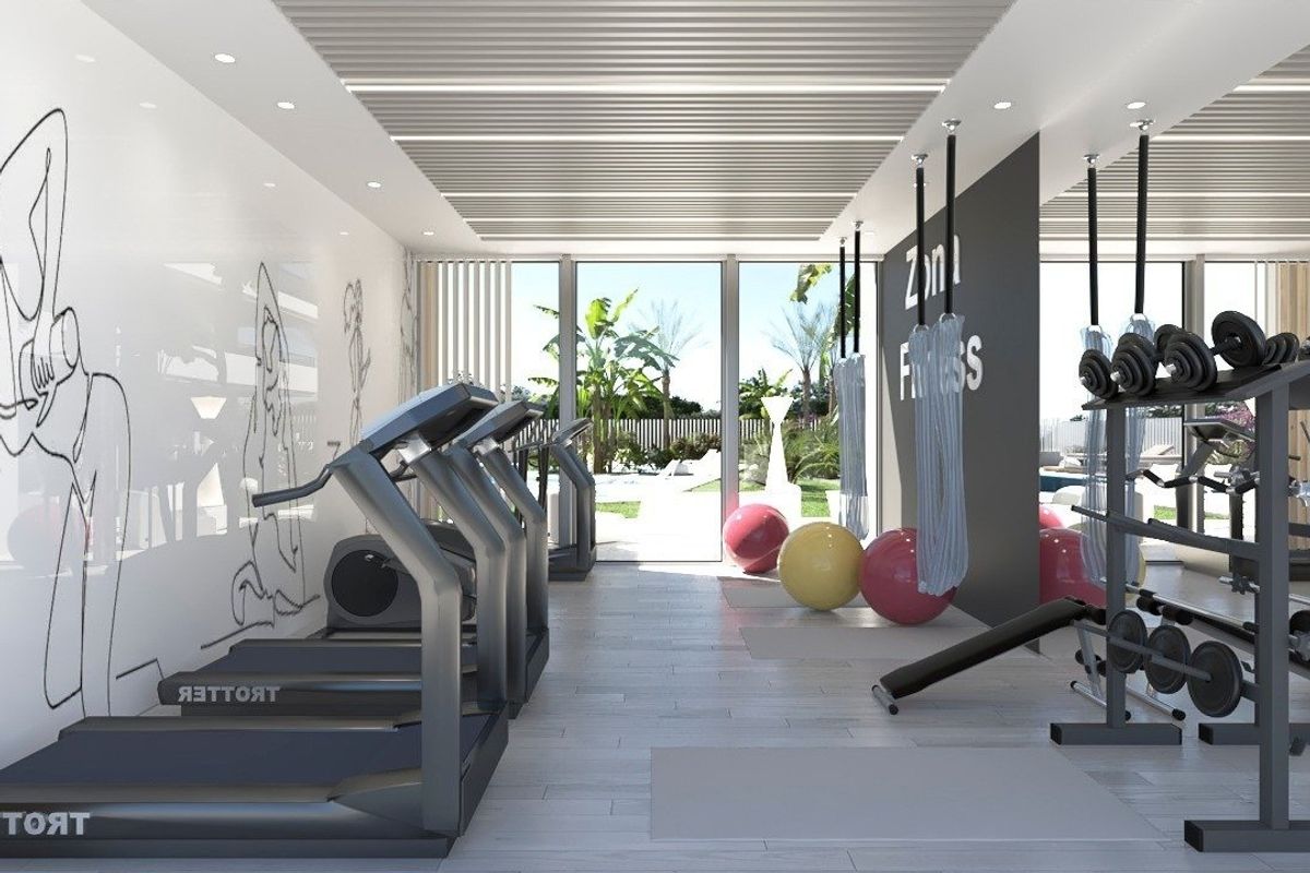 Moderne sportschool met fitnessapparatuur en uitzicht op de tuinen in Orihuela Costa, Spanje.
