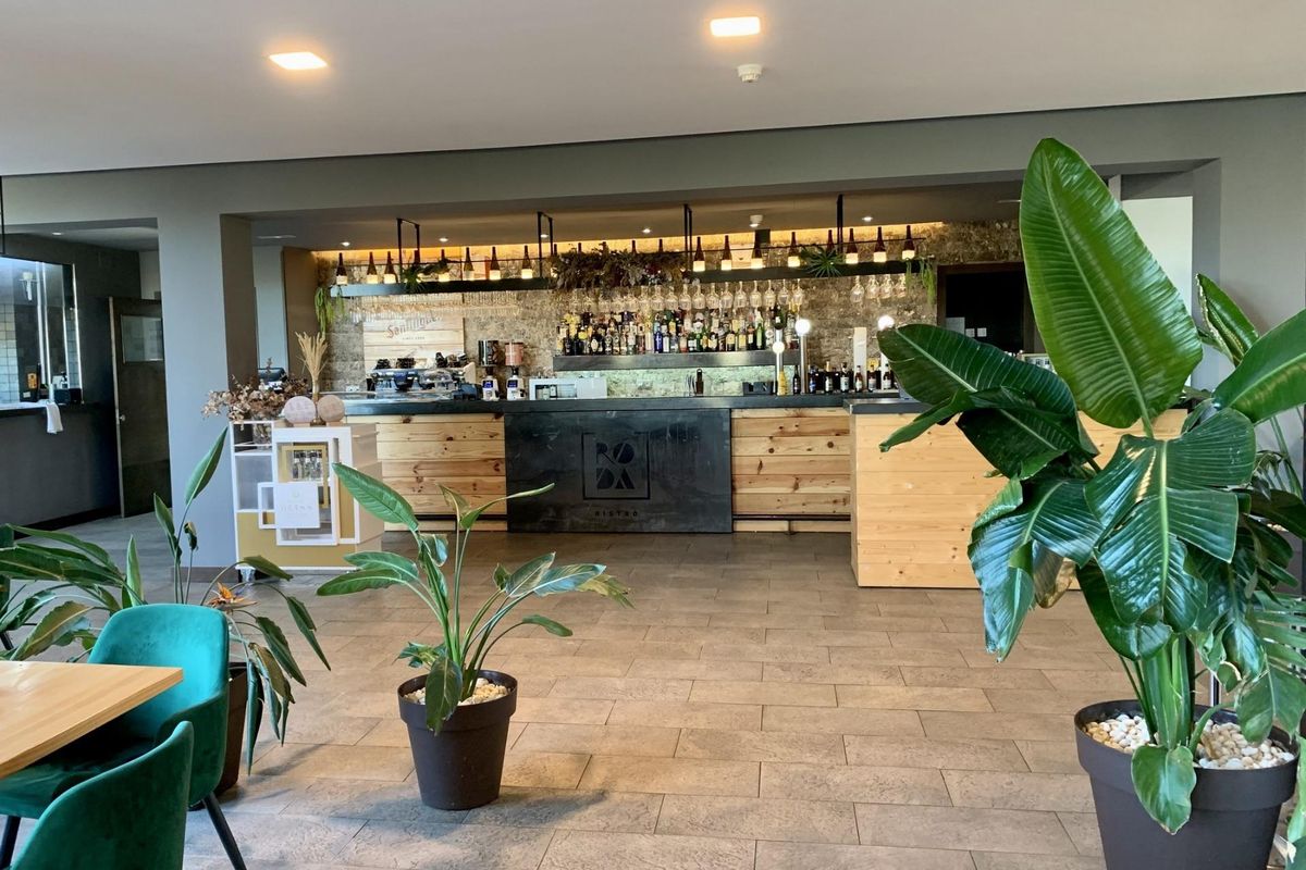 Interieur van een bar met houten decor en planten in de gemeenschappelijke ruimte van het appartementencomplex.