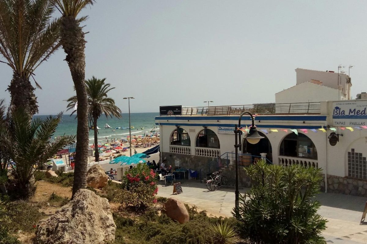 Gezellige sfeer van een restaurant aan het strand met palmbomen en strandgangers nabij Pilar de La Horadada.