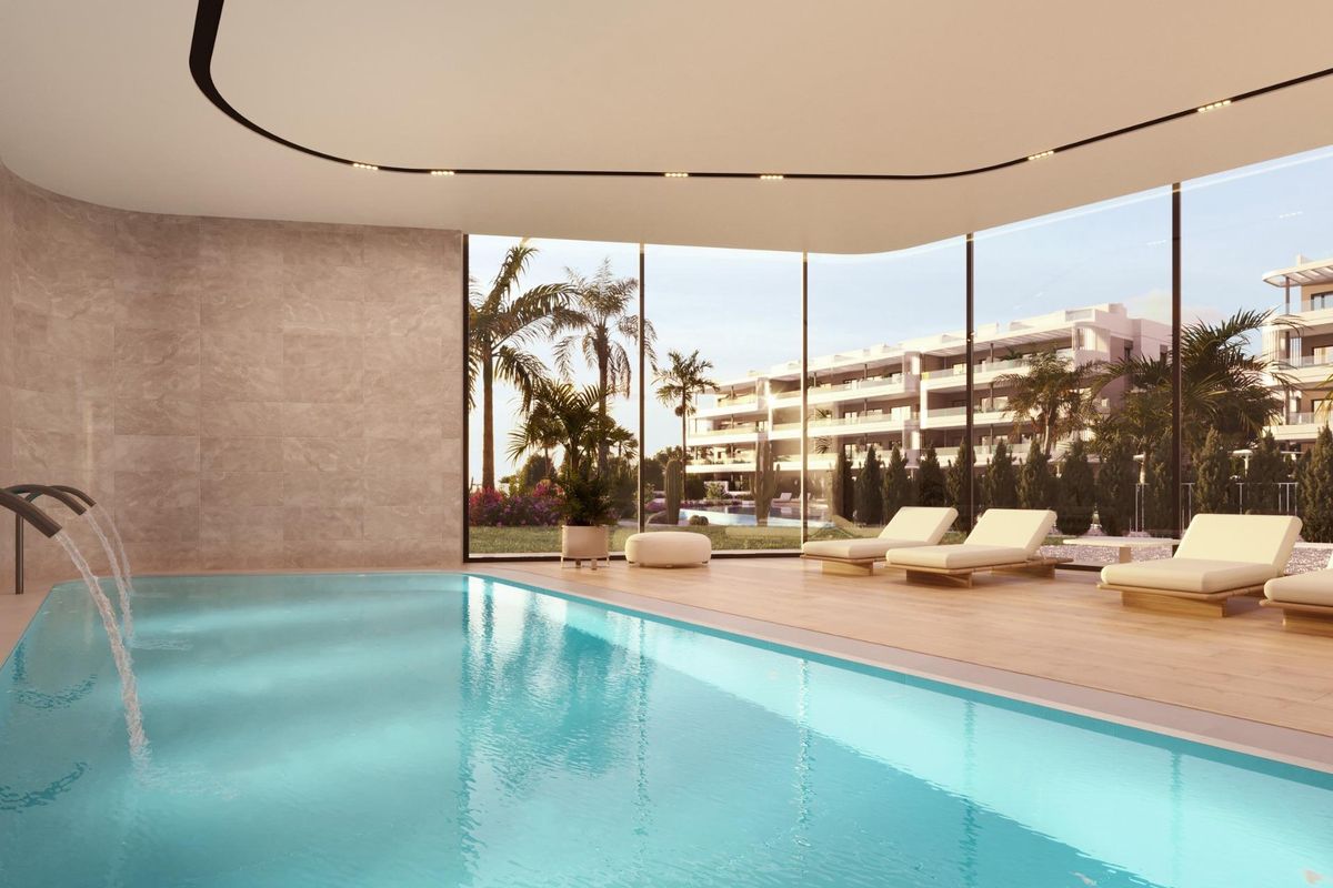 Binnenzwembad met ligbedden en uitzicht op de buitentuinen in een appartementencomplex in Torrevieja.