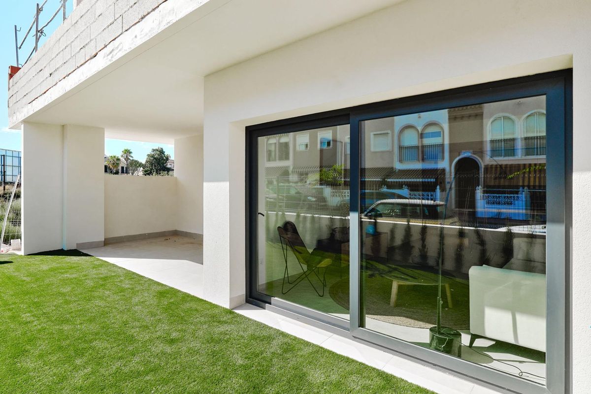 Begane grond terras met moderne glazen schuifdeuren, leidend naar een tuin in Torrevieja, Costa Blanca Zuid.