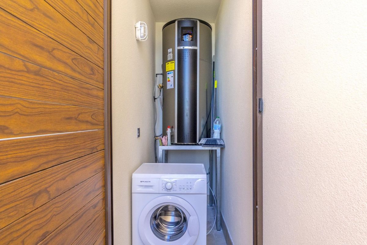 Nutsruimte met wasmachine en boiler in de villa in Rojales.