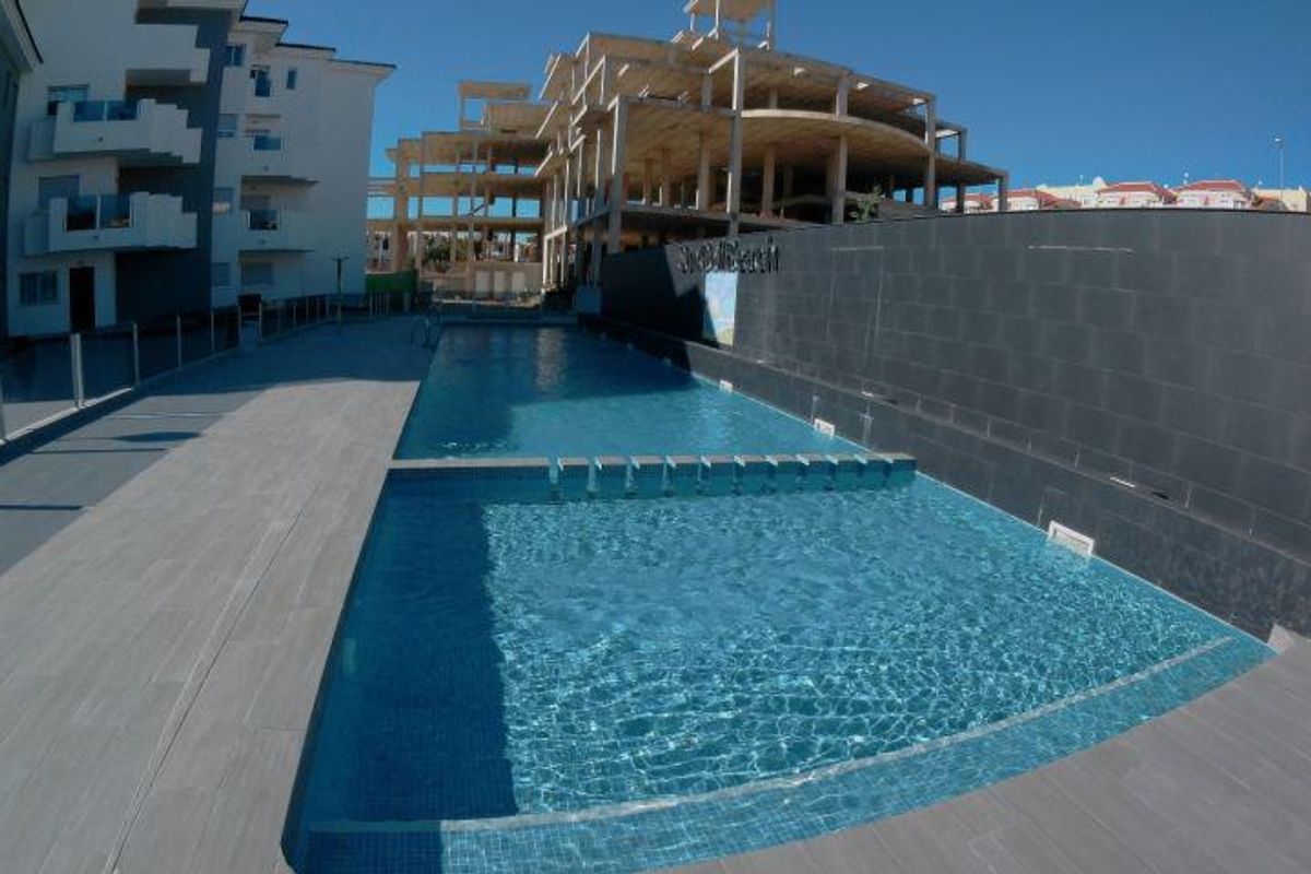 Uitnodigend zwembadgebied bij het appartementencomplex, met helder blauw water in Orihuela Costa.