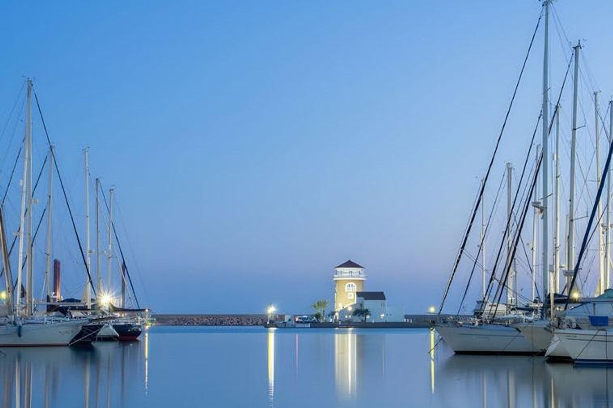 Kalm nachtzicht van de jachthaven met verlichte boten en vuurtoren in Almerimar.