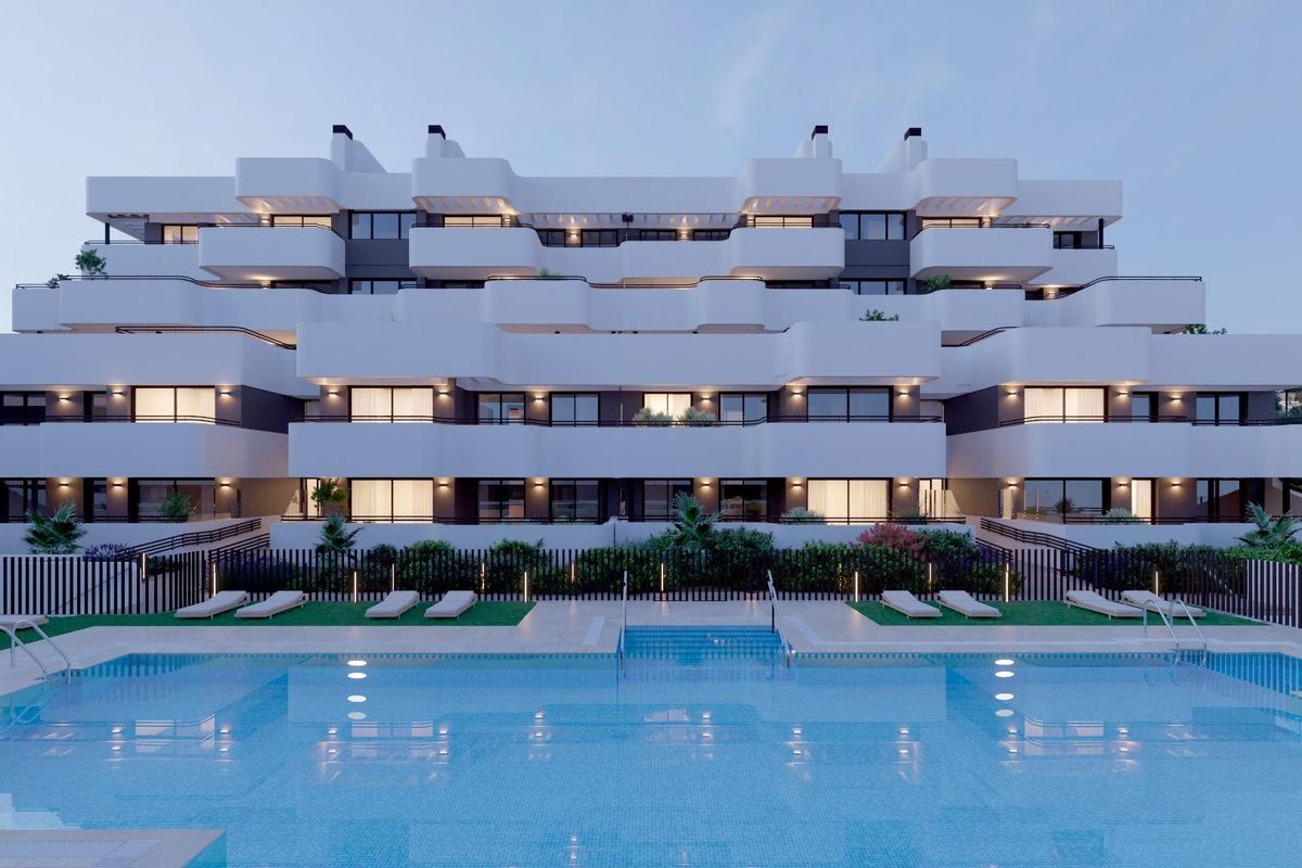 Exterieur van een appartementencomplex in estepona, met een zwembad, ligstoelen en weelderige beplanting. moderne witte architectuur.