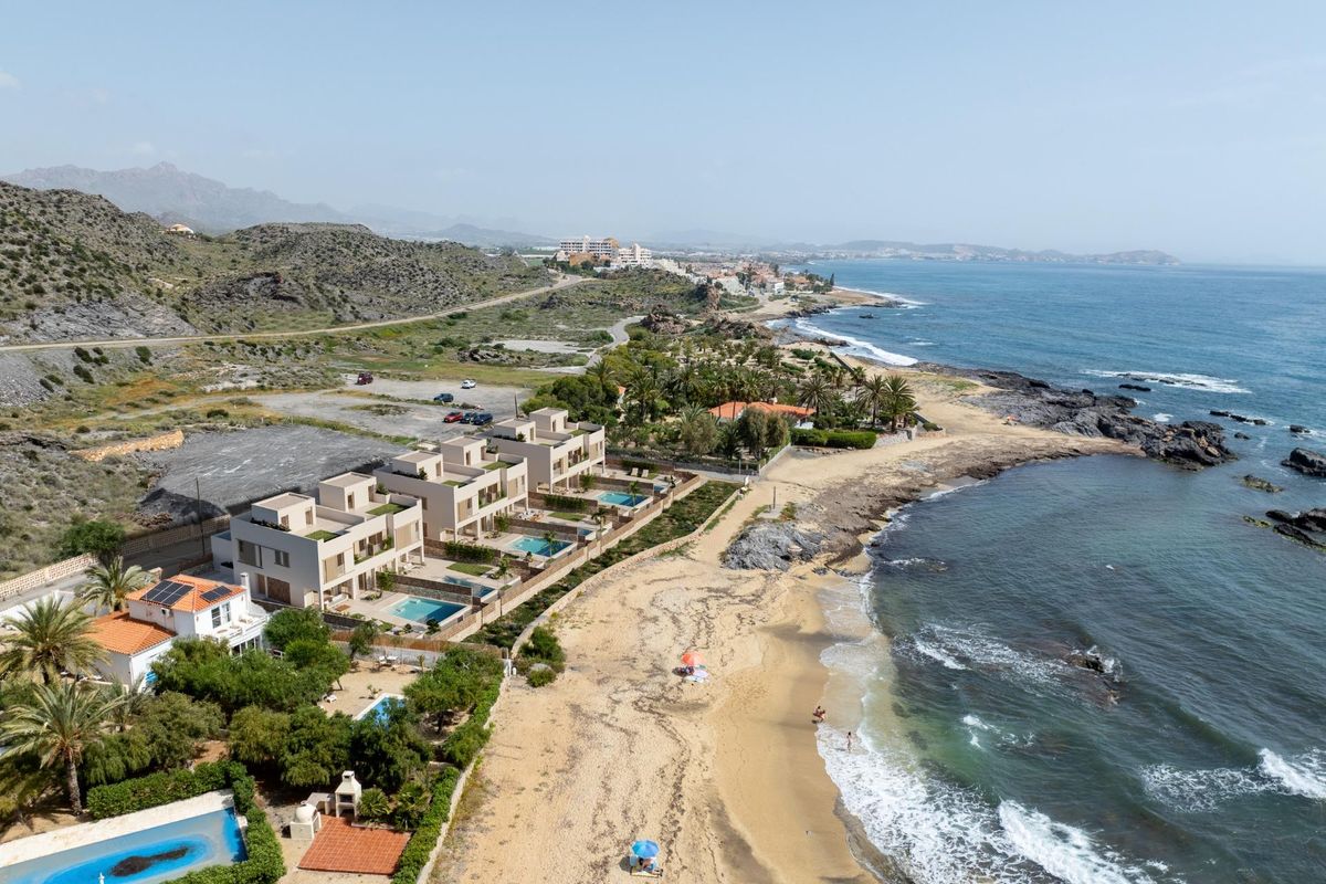 Kustzicht op herenhuizen in Cuevas Del Almanzora, Spanje, met zandstrand en oceaangolven.