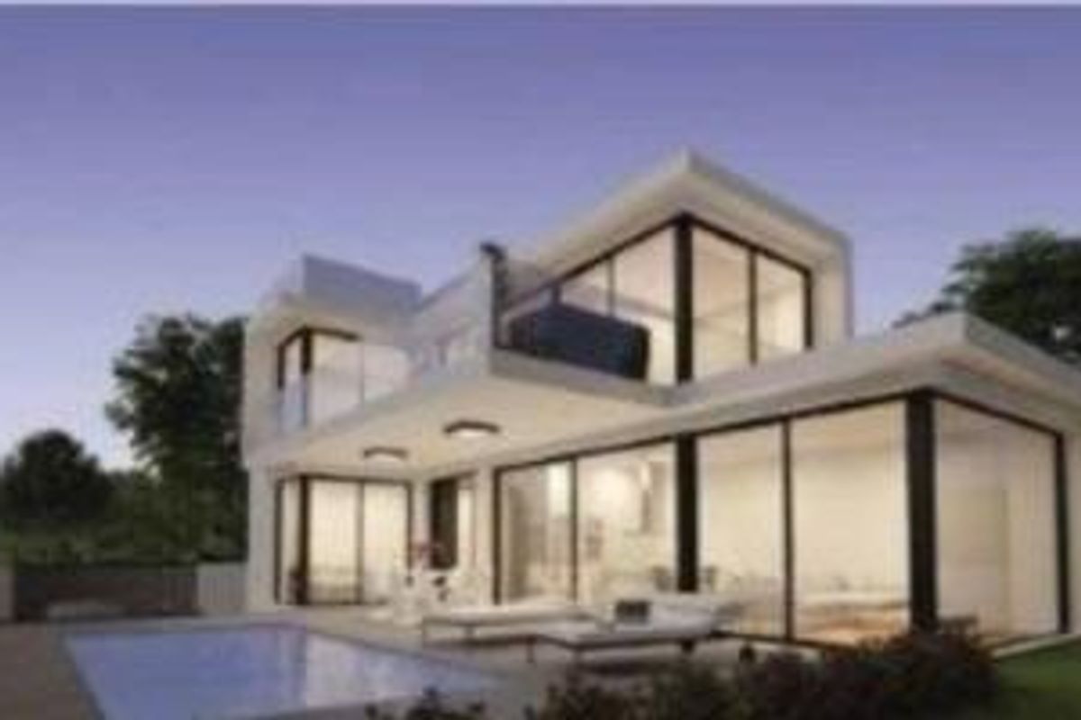 Evening view of a stylish three-bedroom villa in Orihuela Costa, featuring expansive glass walls and a pool.