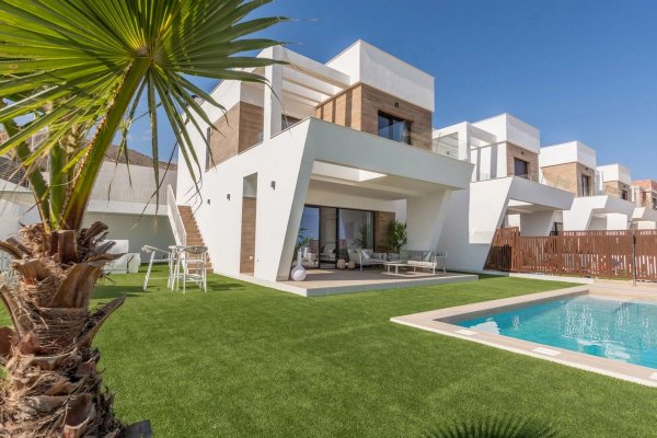 Exterior of a modern 4-bed villa in Finestrat, Spain. View of the pool, garden, and contemporary architecture under a clear blue sky.