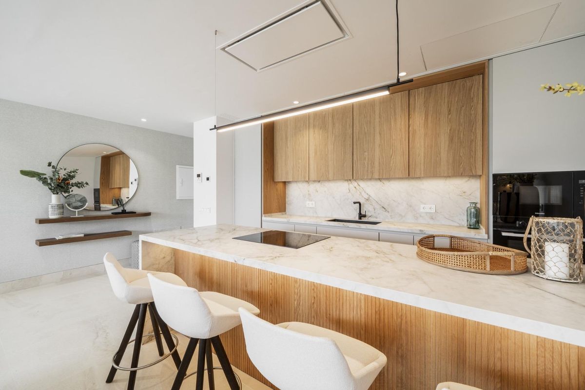 Strakke keuken met marmeren eiland en moderne armaturen, gelegen in een stijlvol appartement in Marbella.