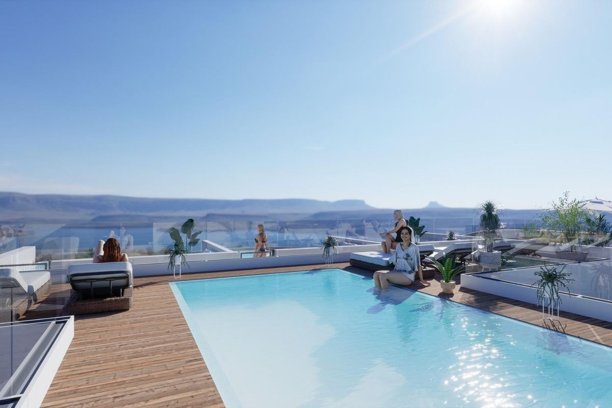 Zwembad op het dak met ligstoelen en ontspannen gasten, met uitzicht in Torrevieja.