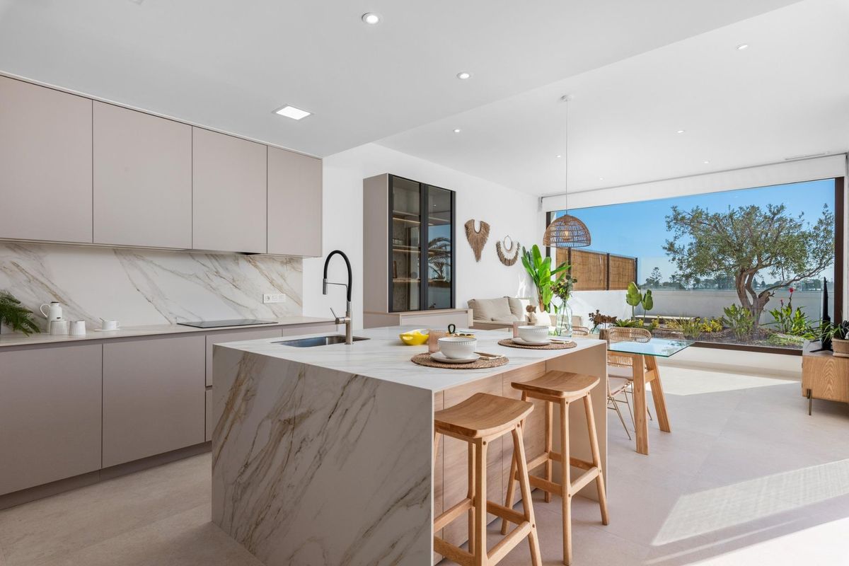 Moderne keuken in de villa met een eiland en eetgedeelte, uitzicht op de tuin in Los Alcazares.