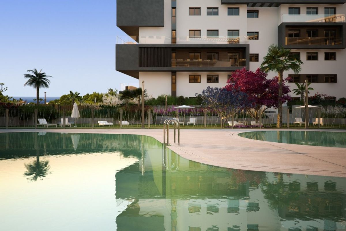 Moderne pool area van een 3-slaapkamer appartement in Orihuela Costa, omgeven door kleurrijke beplanting.
