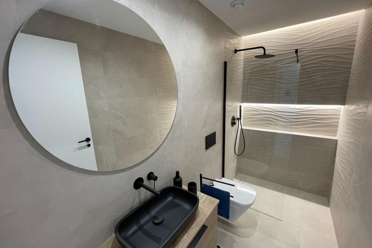 Eigentijdse badkamer in villa molina de segura, met een ronde spiegel, inloopdouche met strakke zwarte armaturen.