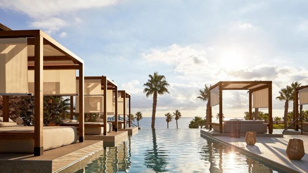 Infinity pool met ligstoelen en palmbomen, uitkijkend over de zee in Mojacar, Costa de Almeria.