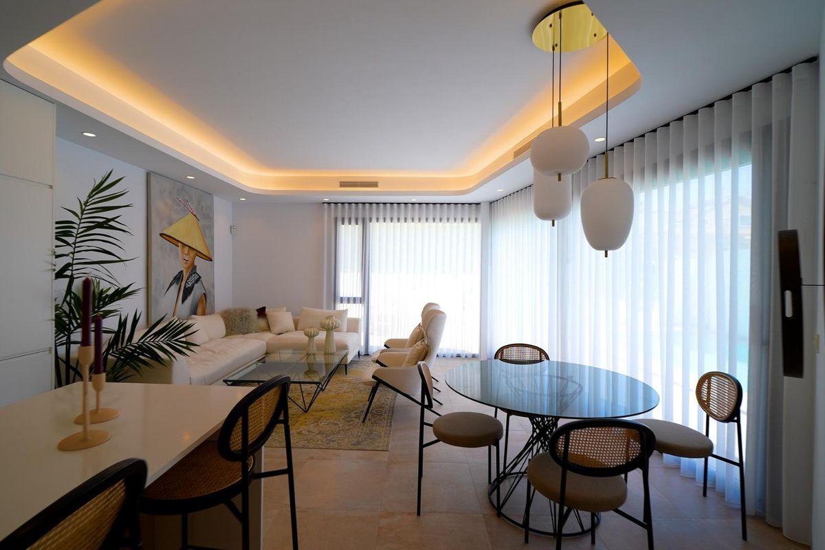 Open eet- en woonkamer met moderne decoratie en grote ramen in een 3-slaapkamer villa, Orihuela Costa, Spanje.