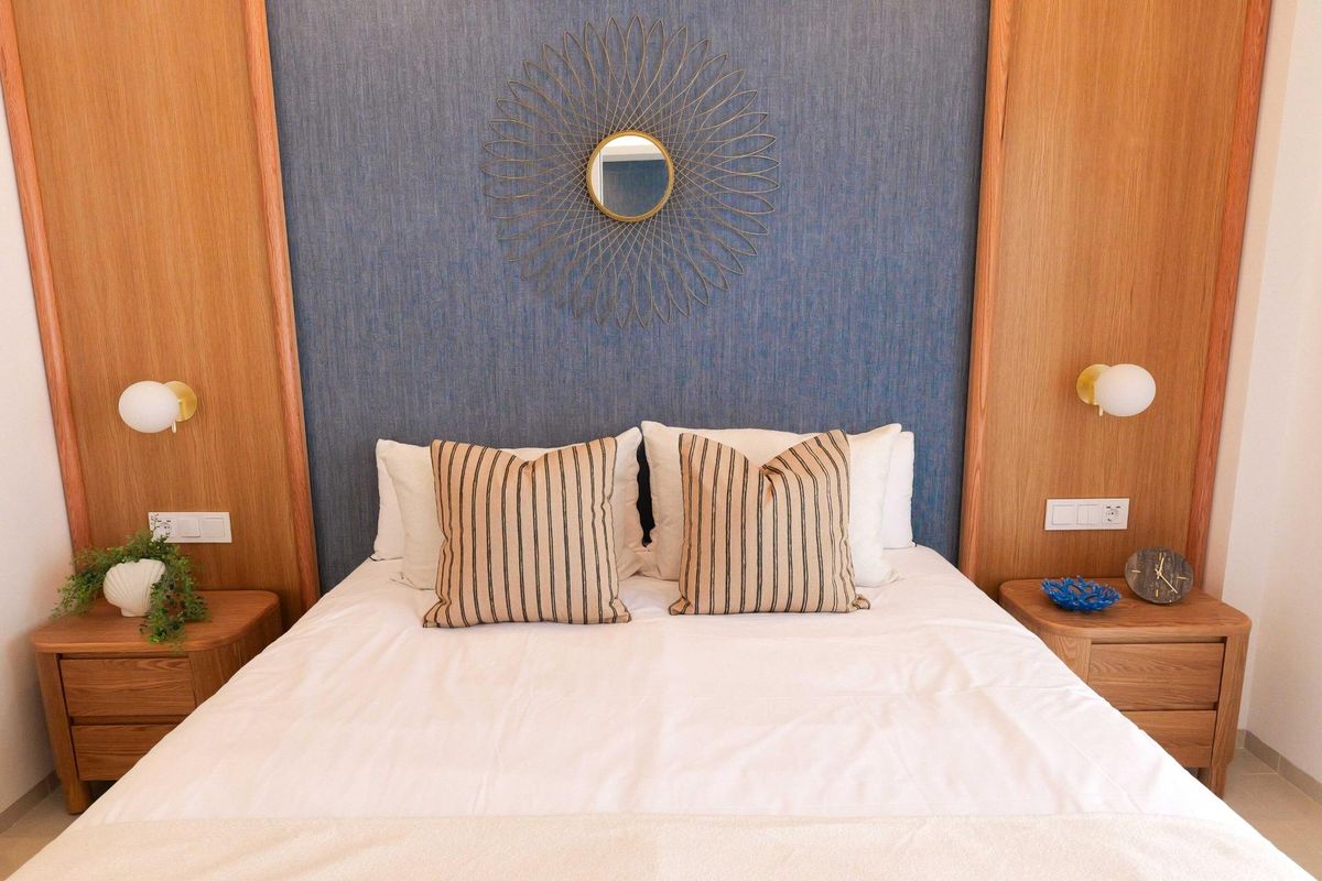 Stijlvolle slaapkamer met een decoratieve muur en zachte meubelen in een appartement op de begane grond in Rojales.