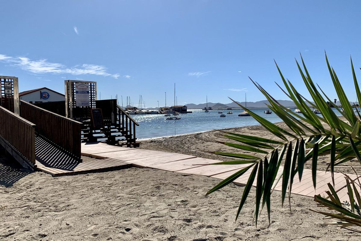 Houten loopbrug naar het strand met boten in de kalme wateren van Los Alcazares.