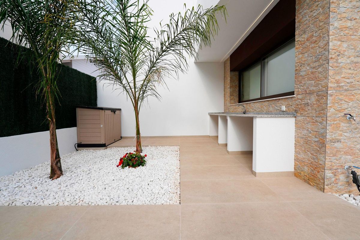 Tuinaanzicht naast het zwembad van een moderne 3-slaapkamer townhouse in Almoradi, met palmbomen.