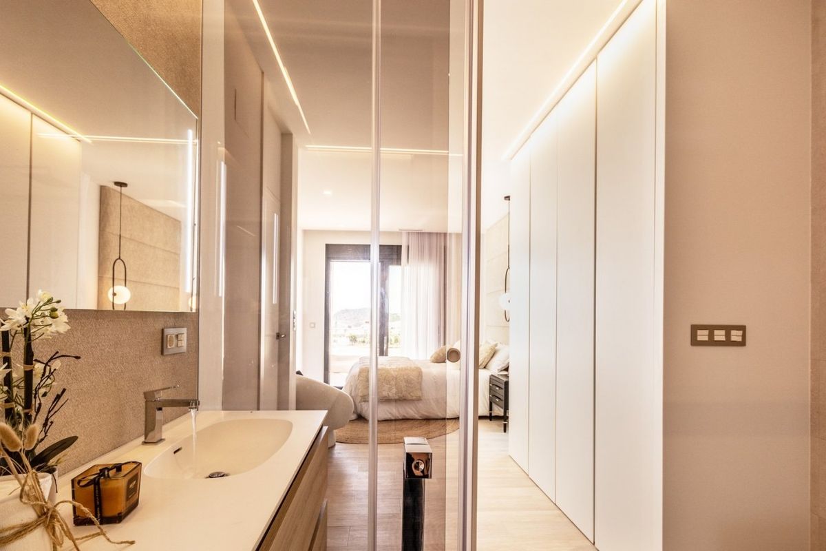 Elegant bathroom in a villa in Finestrat, Costa Blanca. View through glass doors towards a modern bedroom and mountain view.