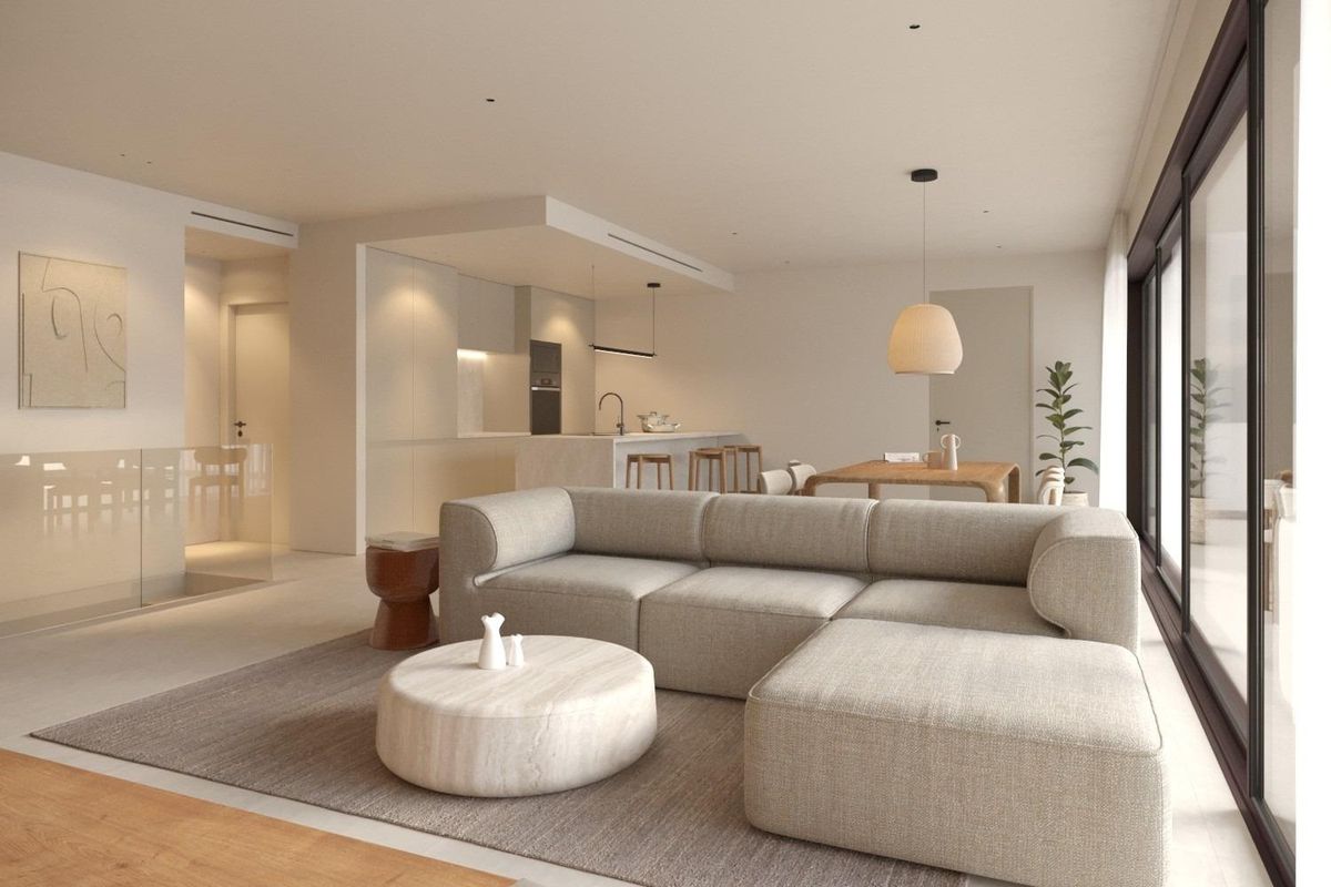 Minimalistische woonkamer met lichtgrijze hoekbank, rond salontafel en subtiele interieurinrichting in neutrale tinten