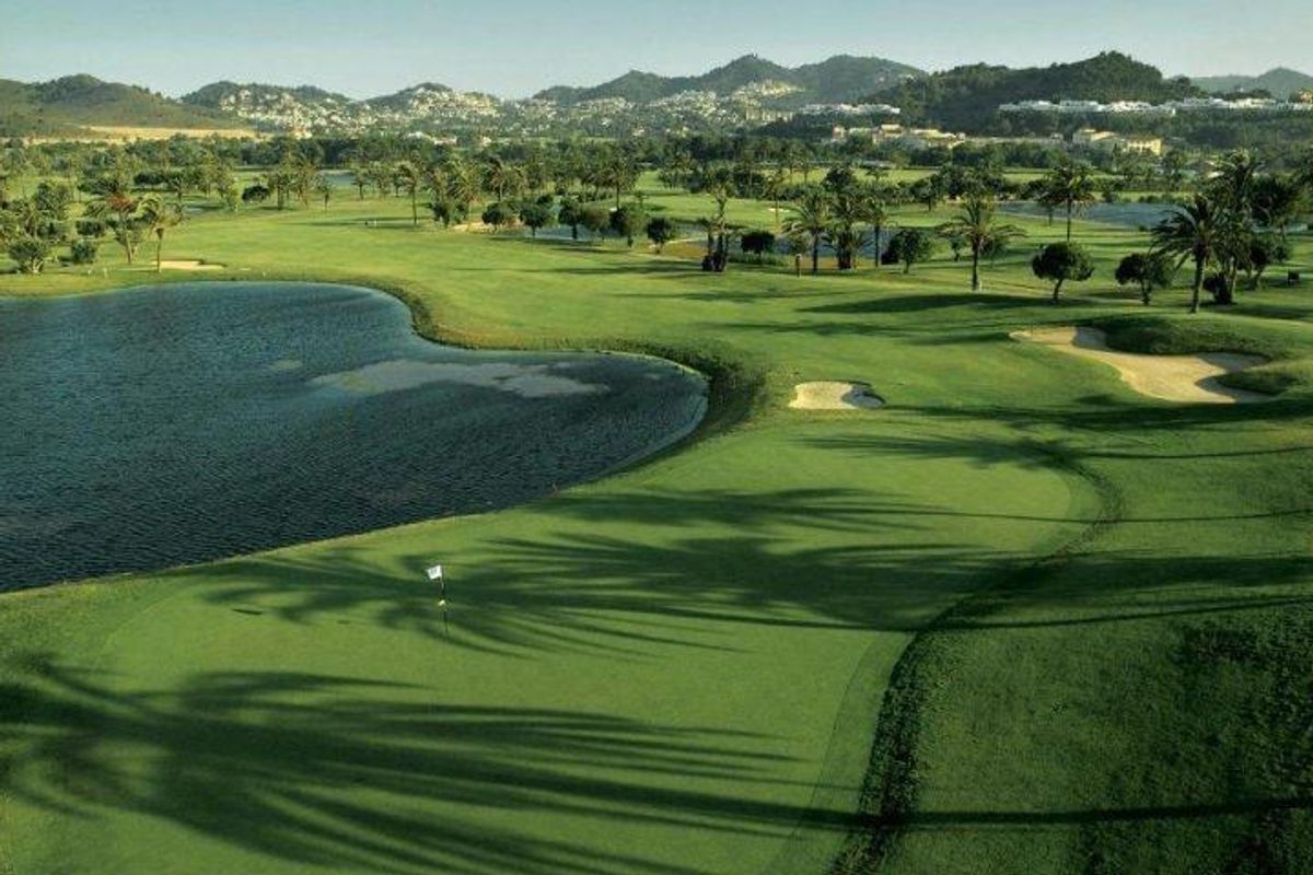 Weelderig groen golfcomplex met waterpartijen en bergen op de achtergrond nabij La Manga del Mar Menor.