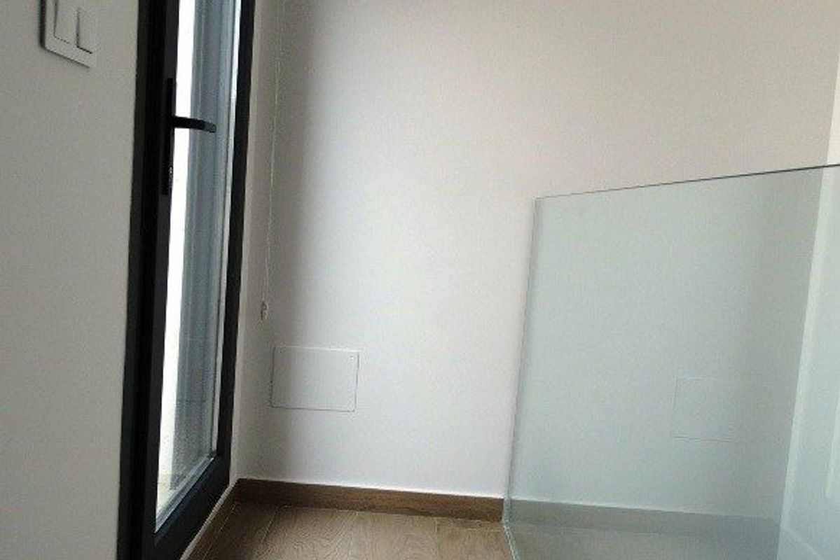 Een hoek van de townhouse met houten vloeren en een glazen barrier nabij de trap in Pilar de La Horadada.