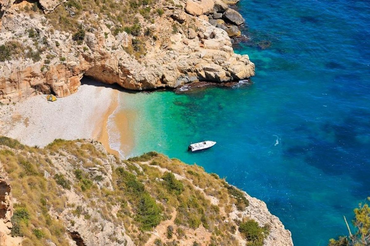 Een serene baai met turquoise water en een afgelegen strand, die de prachtige landschappen van Costa Blanca Noord benadrukt.