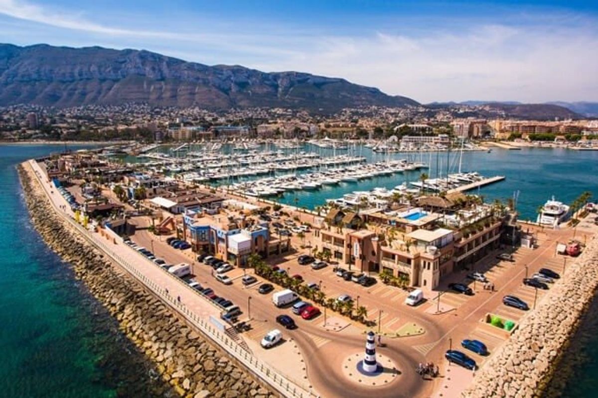 Aerial view of Denia revealing its vibrant waterfront and surrounding mountains.