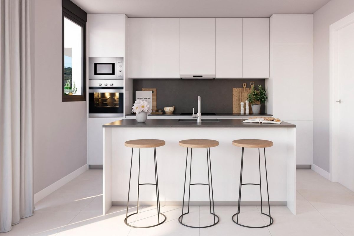 Moderne keukenset met elegante werkbladen en barstoelen in het appartement in Casares.
